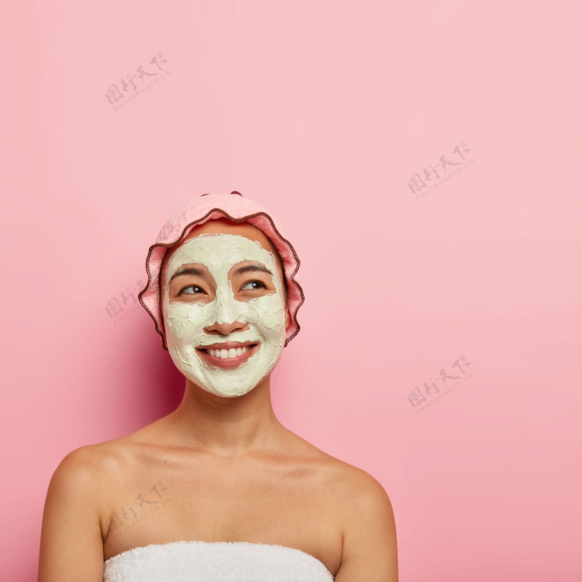 面膜专业的护肤理念快乐的民族女性用面膜来清洁和滋润皮肤 用梦幻般的快乐表情 露出微笑 裹在柔软的毛巾里 摆在室内愉悦护肤满意