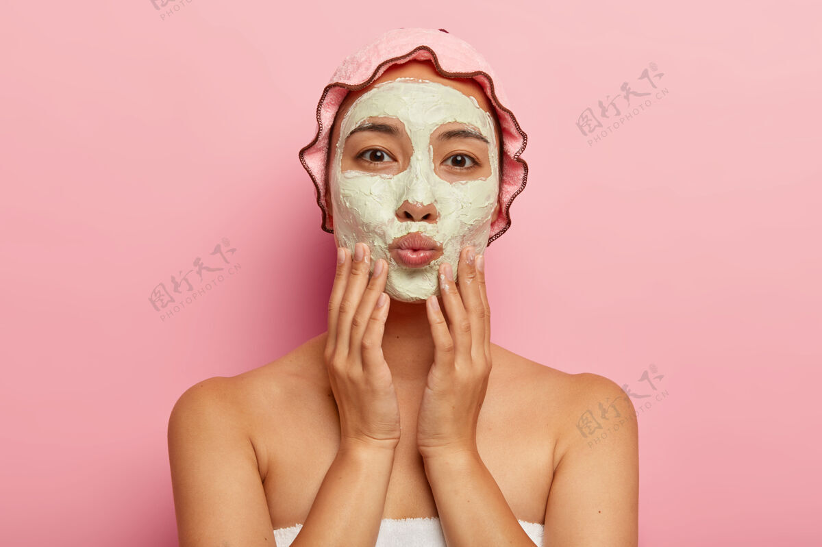 沐浴用可爱的化妆面膜贴近可爱的亚洲女人的肖像 轻轻抚摸脸部 保持嘴唇的折叠 直视 享受清洁和美容护肤品皮肤卫生面部