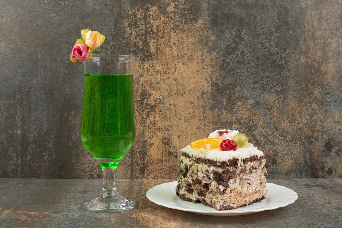 果汁在大理石墙上放一块蛋糕和一杯多汁的绿色柠檬水杯子派饮料