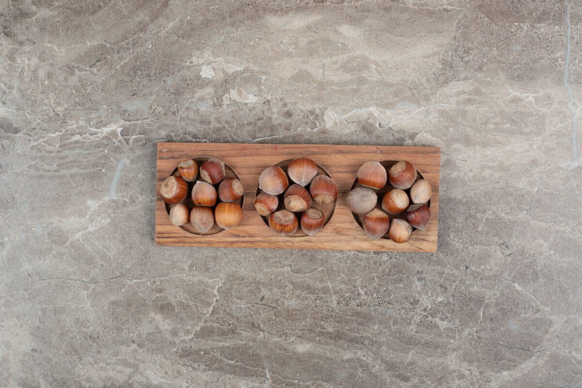坚果一堆榛子放在大理石墙上的木板上新鲜美味贝壳