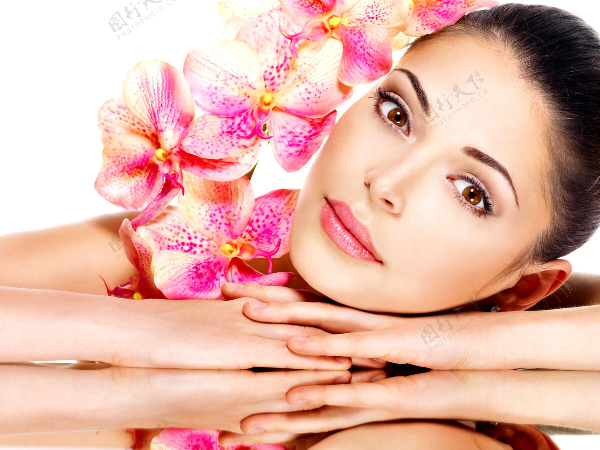 花年轻漂亮的女人美丽的脸 健康的皮肤和粉红色的花-隔离在白色漂亮皮肤护理