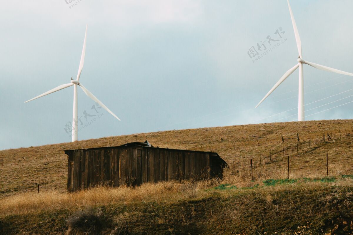 农村在白天的阳光下 田野里有两个风车的旧木屋农场有机田地