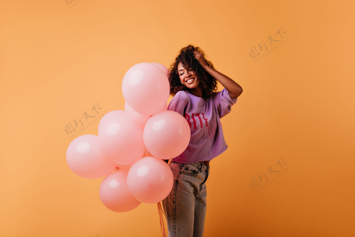 人迷人的黑发女孩与粉红色气球摆出愉快的姿势可爱的黑色女士在她的生日冷气球节日卷发