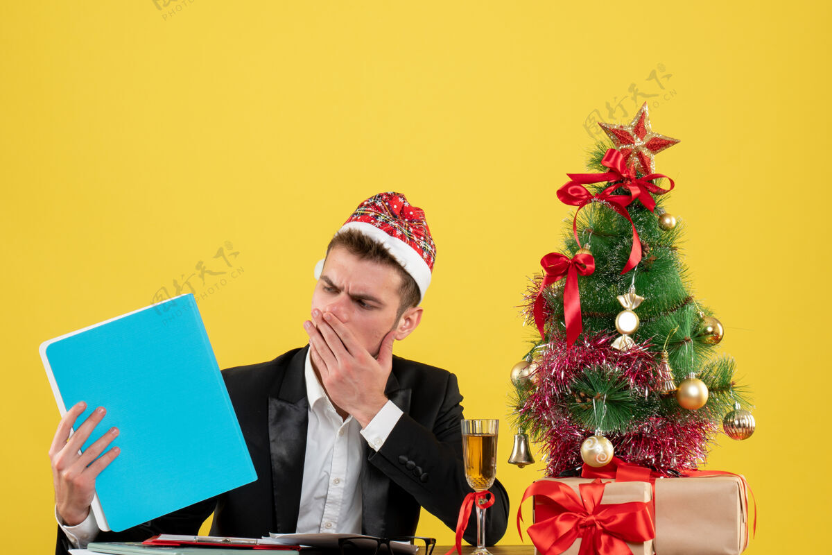 工人正面图：男工人拿着文件围着圣诞树 黄色的礼物圣诞树工作