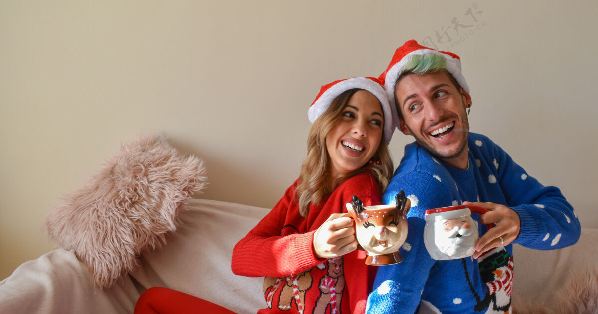 礼物拍摄一对幸福的夫妇在圣诞节小屋和衣服举行有趣的杯子男人杯子爱情