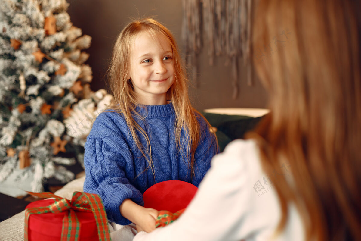 家人们在为圣诞节做准备母亲在和女儿玩耍一家人在节日的房间里休息孩子穿着蓝色毛衣女儿快乐绿色