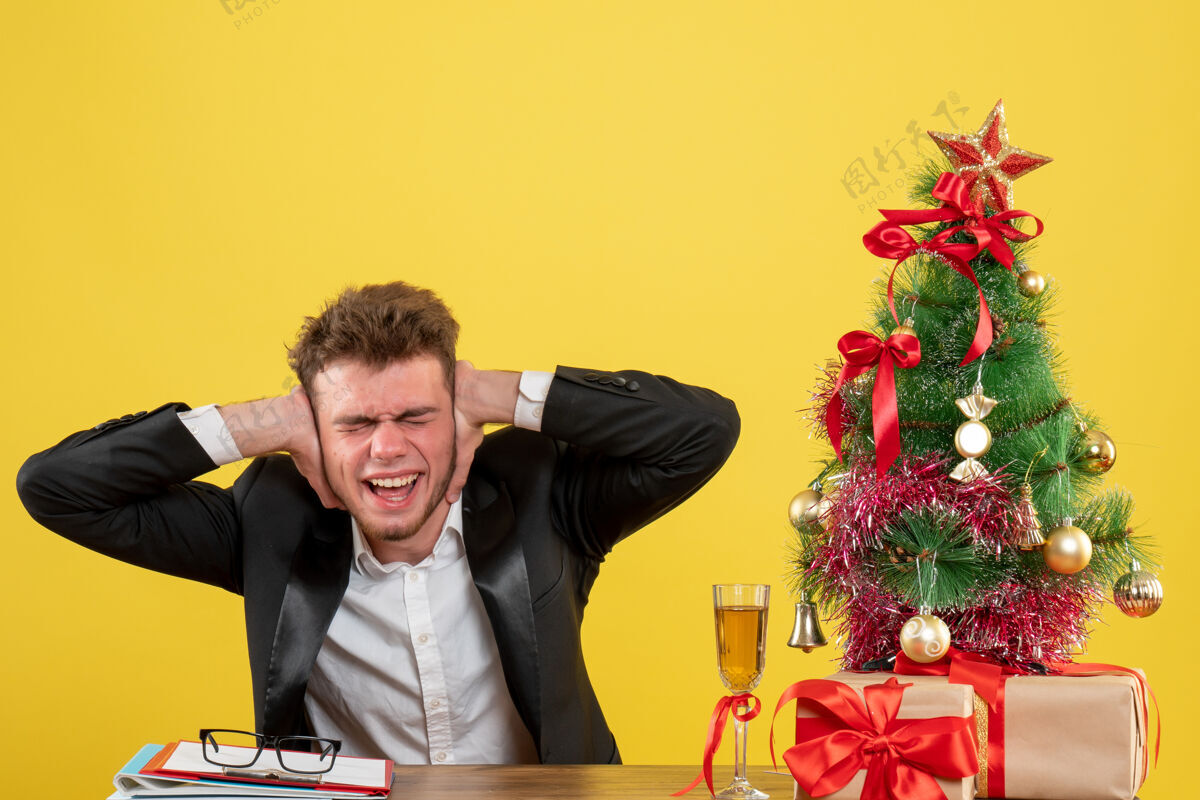 圣诞节正面图：坐在工作场所后面的男工人 耳朵贴着一张黄色的照片主管坐关门