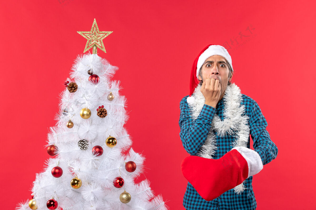 男人一个戴着圣诞老人帽子 穿着蓝色条纹衬衫 穿着圣诞袜子的悲伤的年轻人圣诞老人年轻人年轻