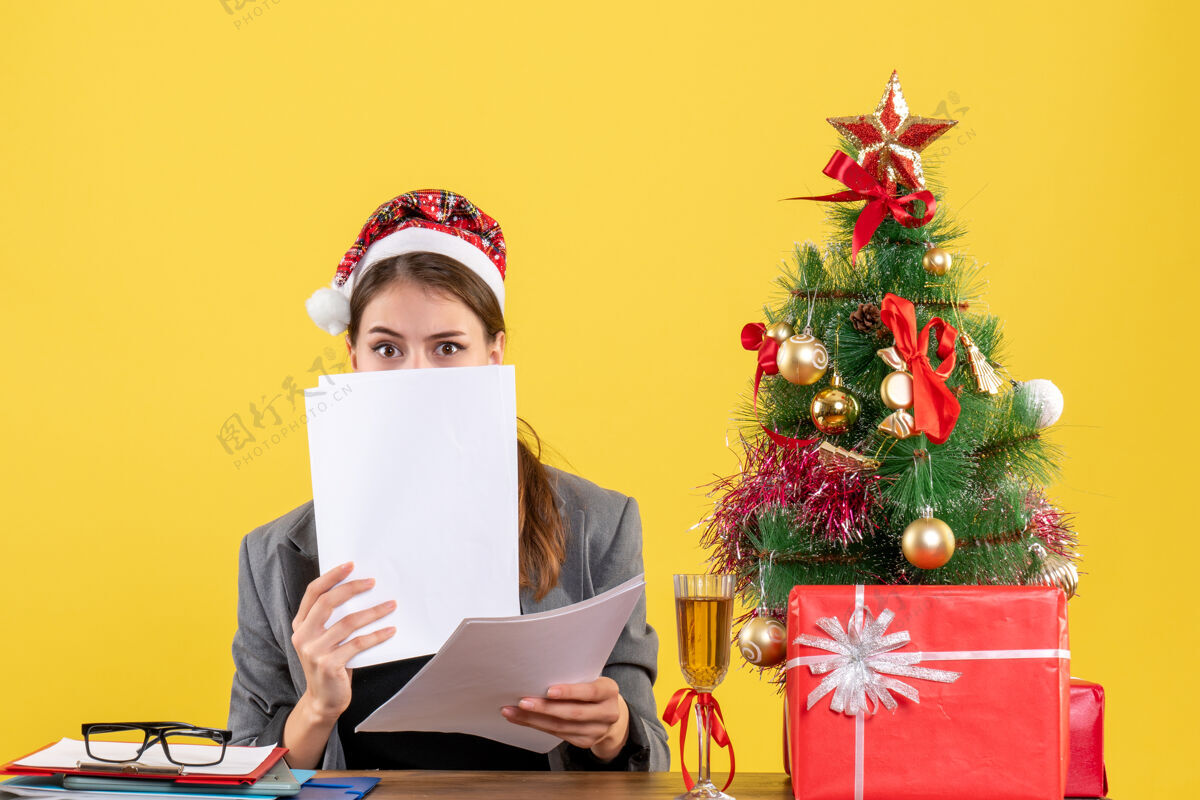 封面正面图：年轻的商务女士 戴着圣诞帽 坐在桌旁 脸上挂着圣诞树和鸡尾酒女士圣诞节树