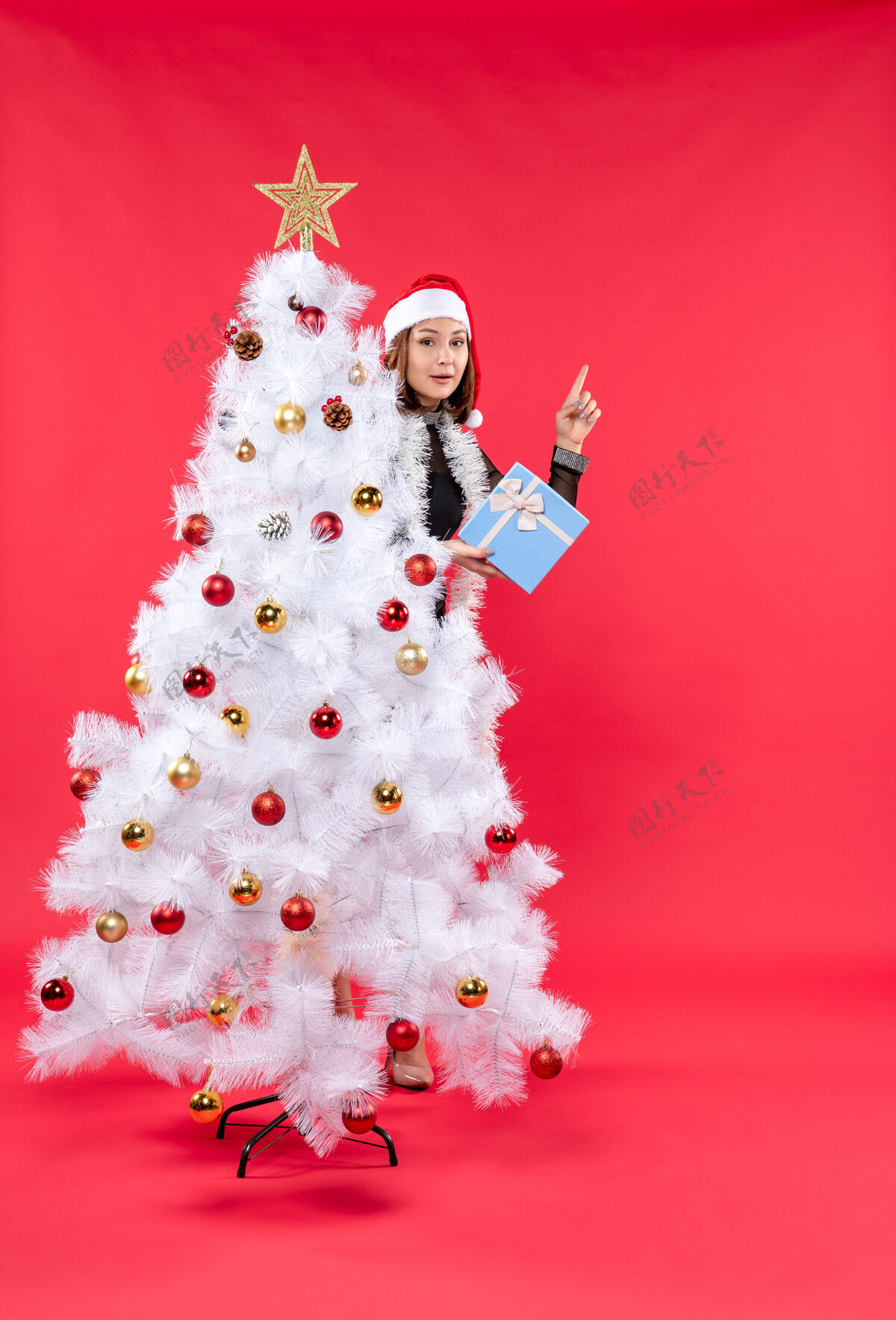 帽子圣诞气氛的俯视图 美丽的女孩穿着黑色连衣裙 戴着圣诞老人的帽子心情站着圣诞