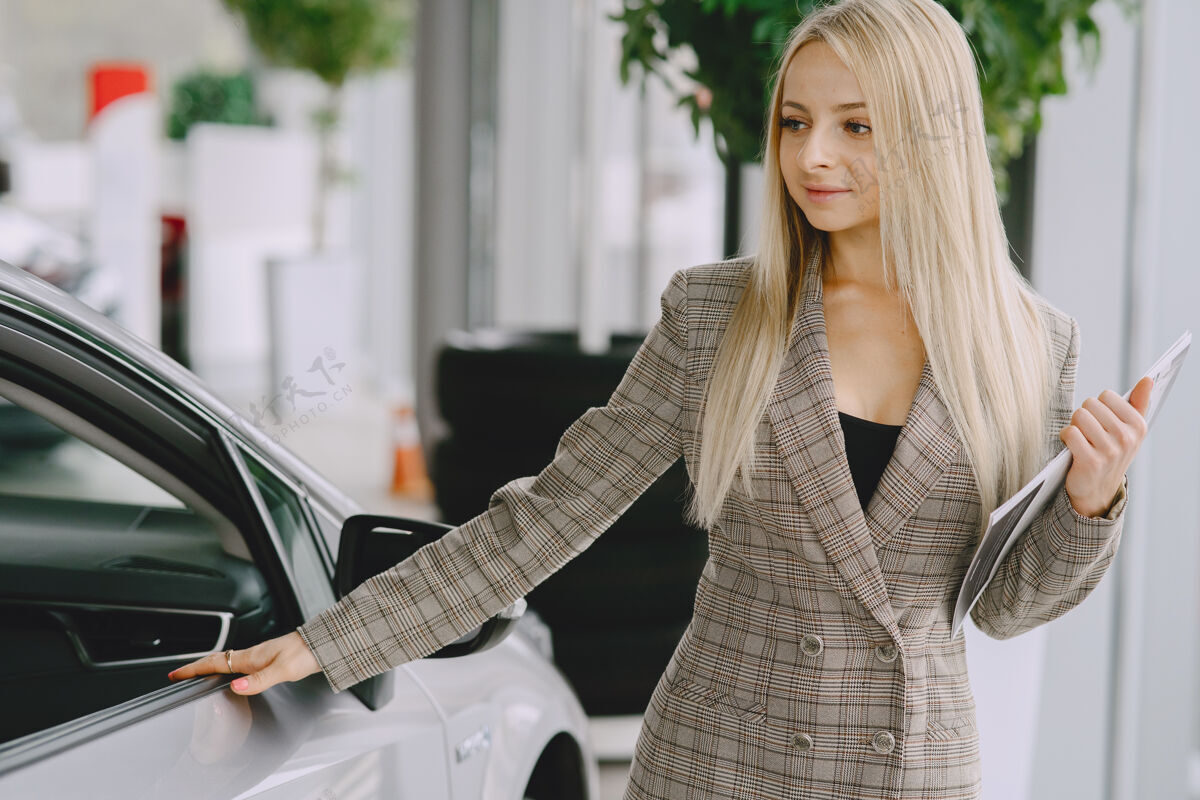 经销商汽车沙龙里的女士买车的女士穿着棕色西装的优雅女士年轻人金发车辆
