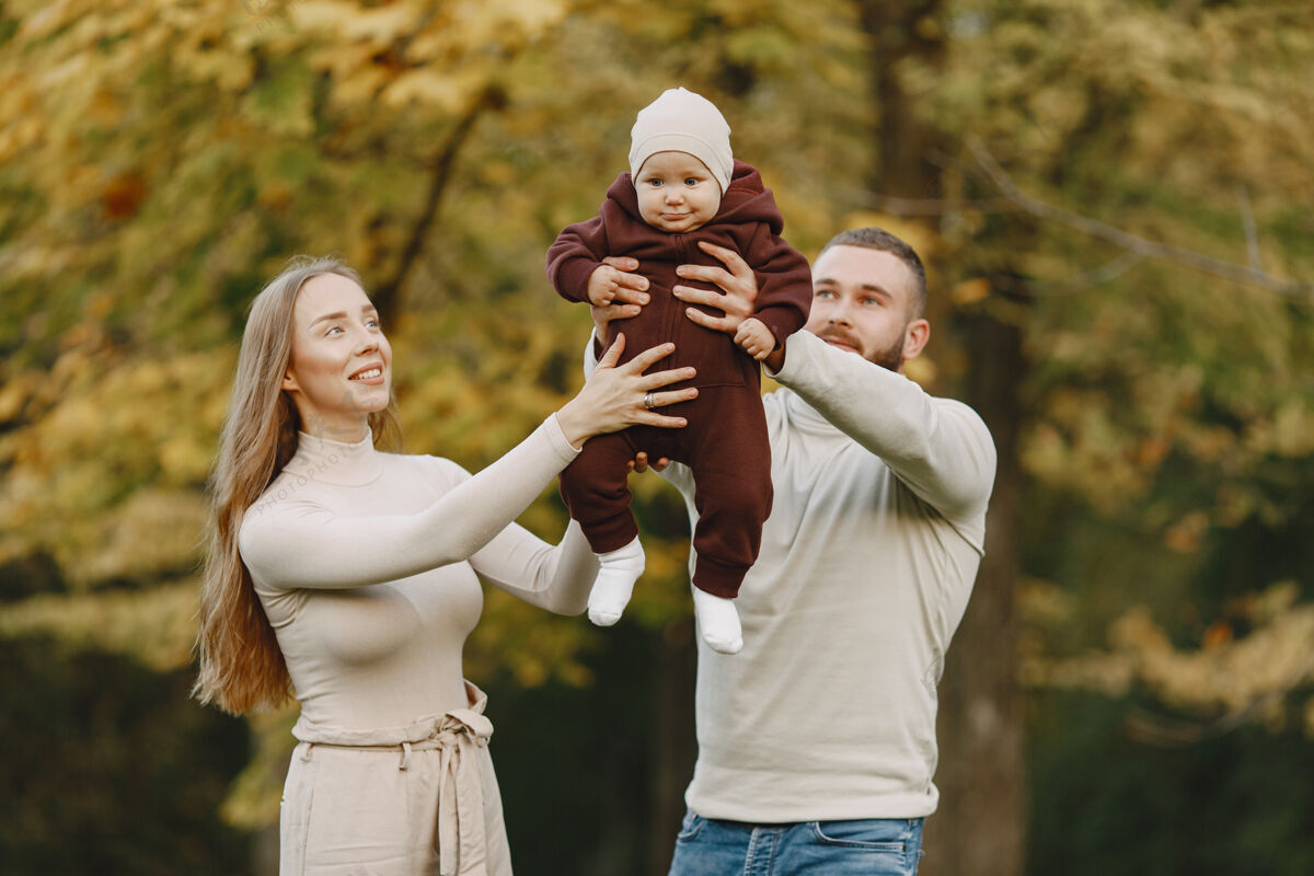 头发秋天公园里的一家人穿棕色毛衣的男人和父母在一起的可爱小女孩三个妈妈胡须