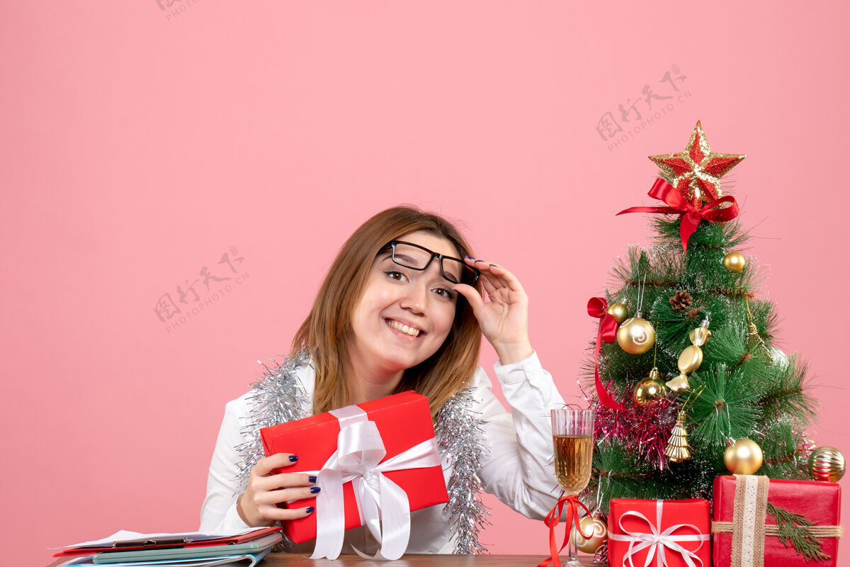人女工手持粉红色礼物的正面图粉色圣诞节女性