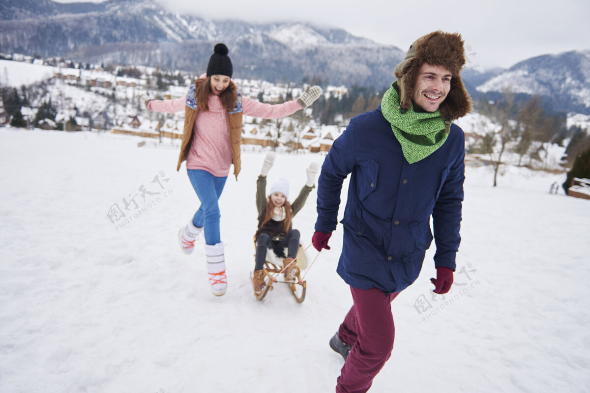 雪橇爸爸拉着女儿上雪橇休息暖衣人群