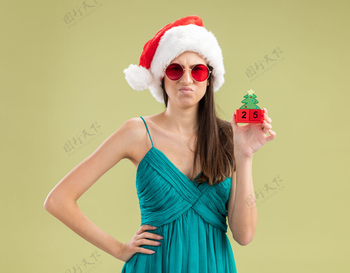 空间戴着太阳眼镜 戴着圣诞帽 拿着圣诞树饰物的年轻白人女孩帽子圣诞快乐装饰