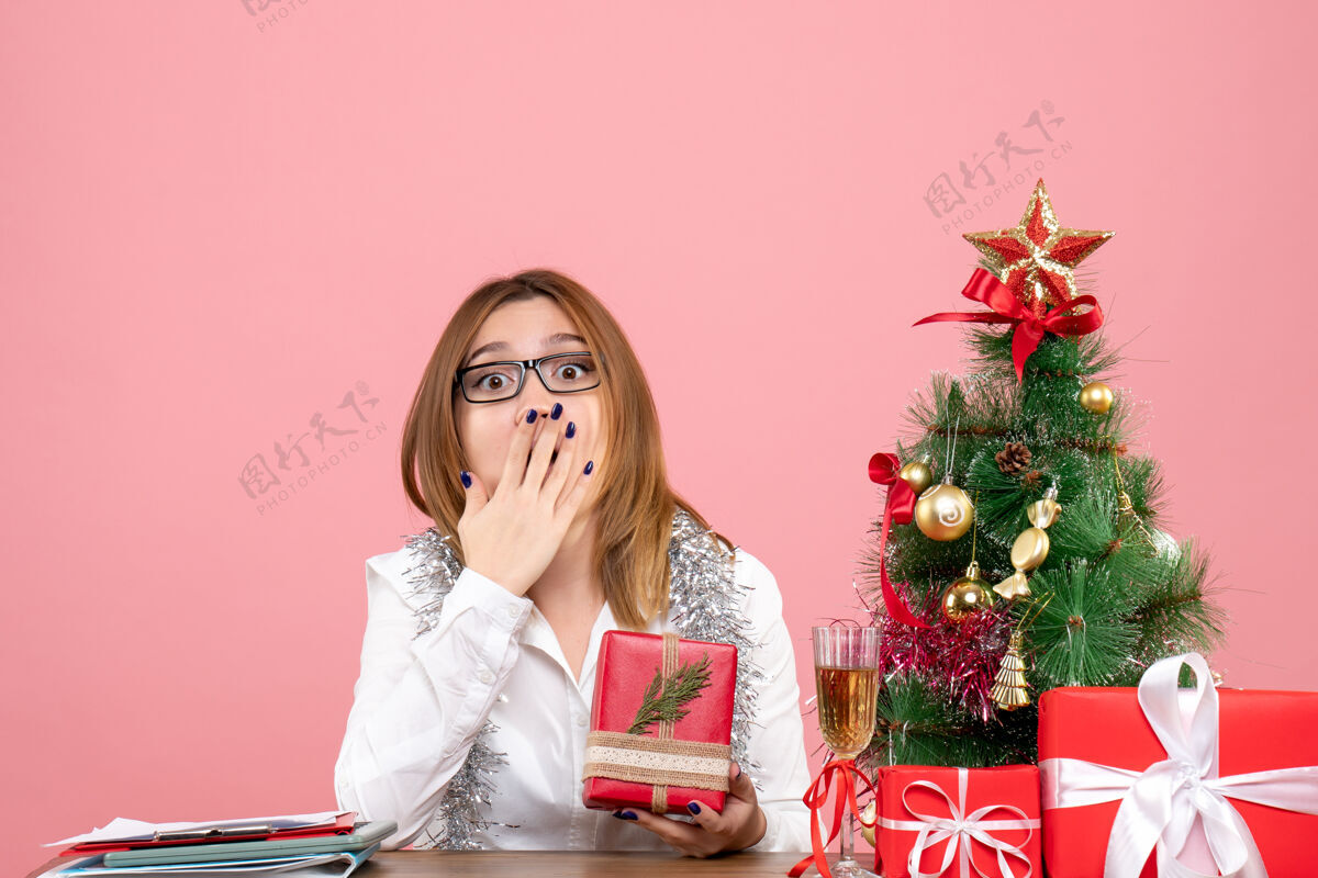 肖像女工正坐在粉红色的椅子上 手里拿着圣诞礼物工作女性成人