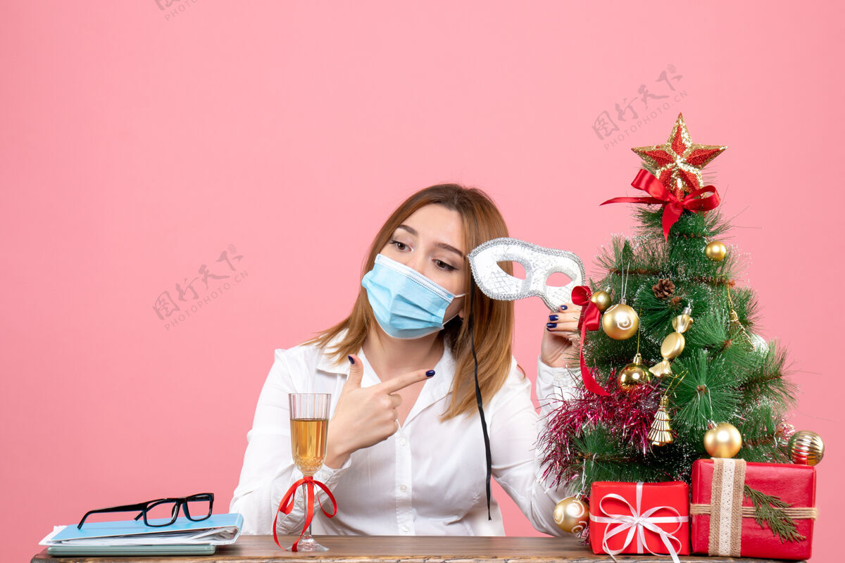 喜剧演员戴着面具的女工坐在桌子后面 粉色的圣诞礼物面具成人女工