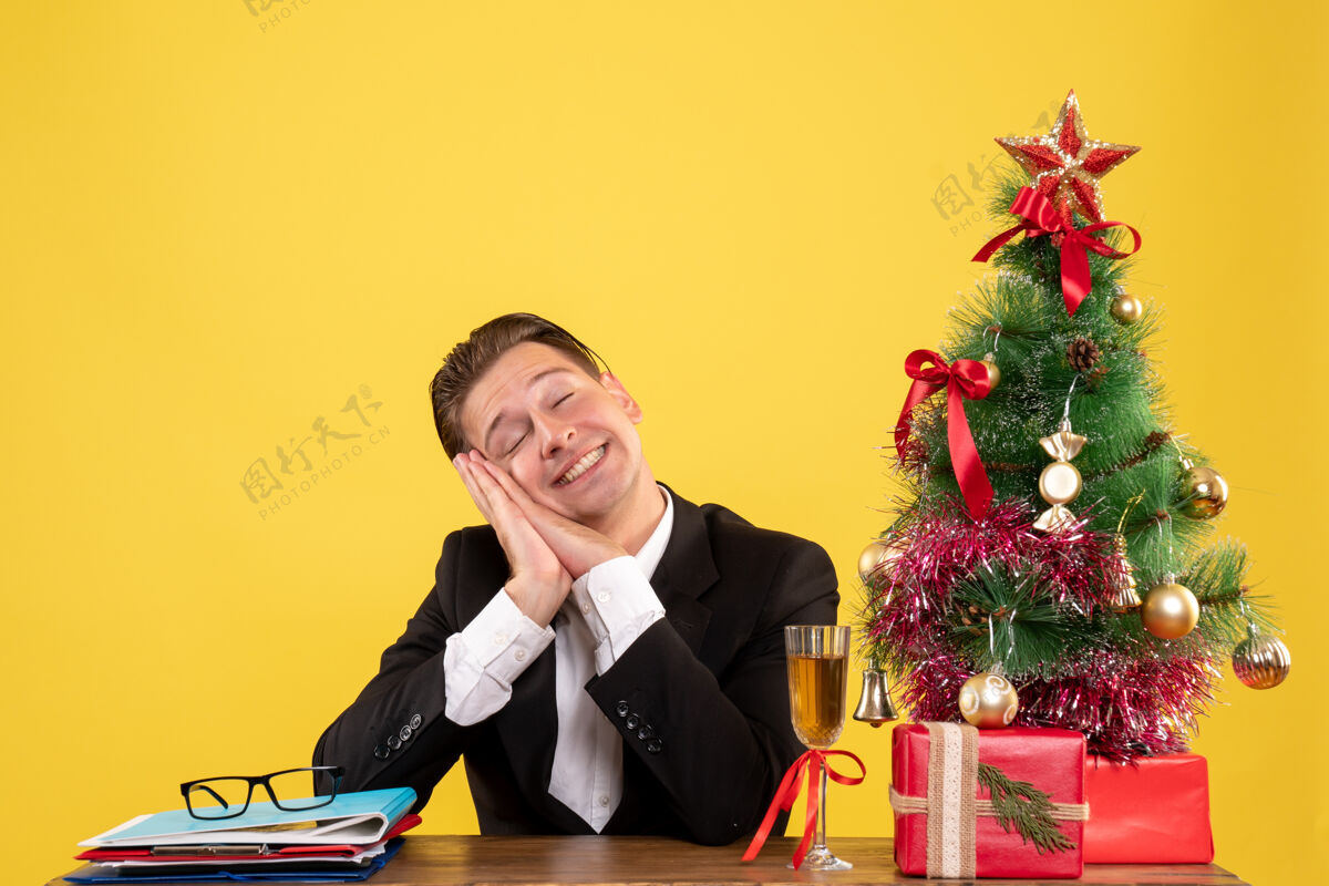 情感正面图年轻的男工人坐在圣诞礼物和树梦主管礼物梦想