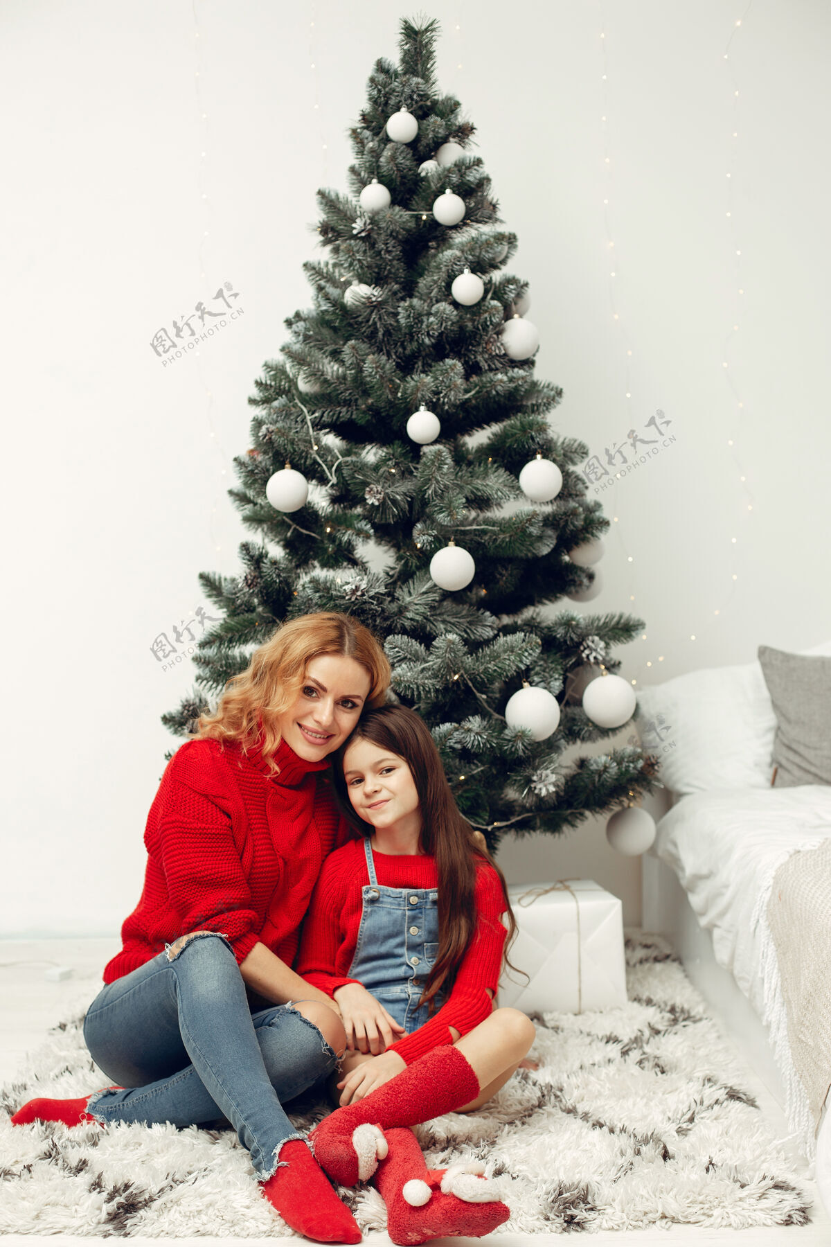 装饰人们在为圣诞节做准备母亲在和女儿玩耍一家人在节日的房间里休息孩子穿着红色毛衣花环孩子女儿