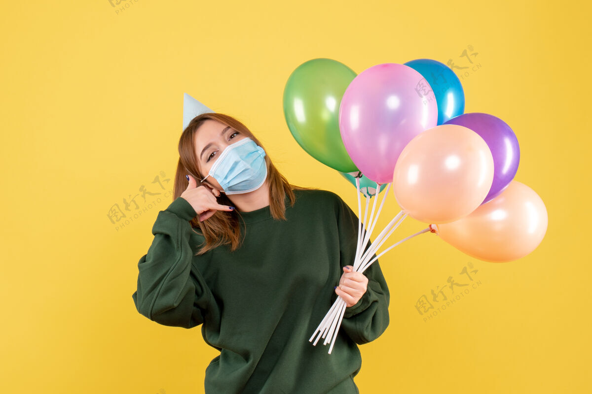 庆祝正面图：手持彩色气球的年轻女性病毒人流行性疾病