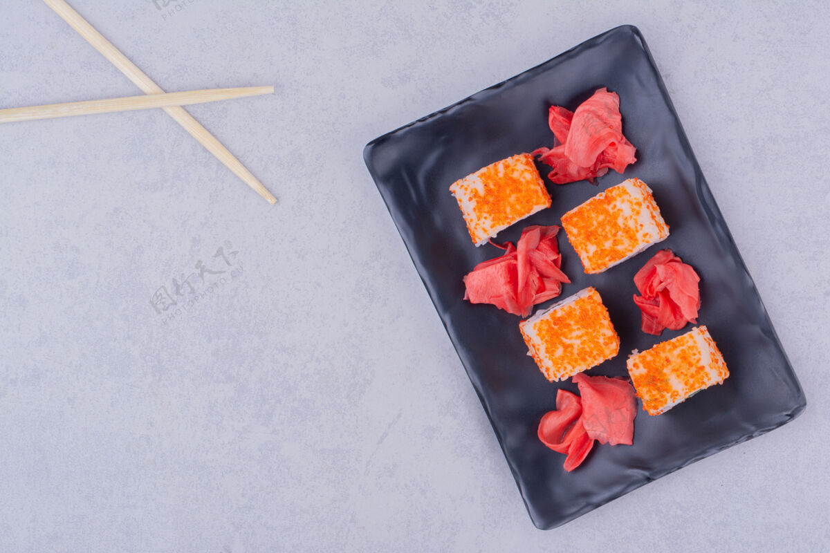 生物黑色陶瓷盘中的鲑鱼寿司卷观点筷子早午餐