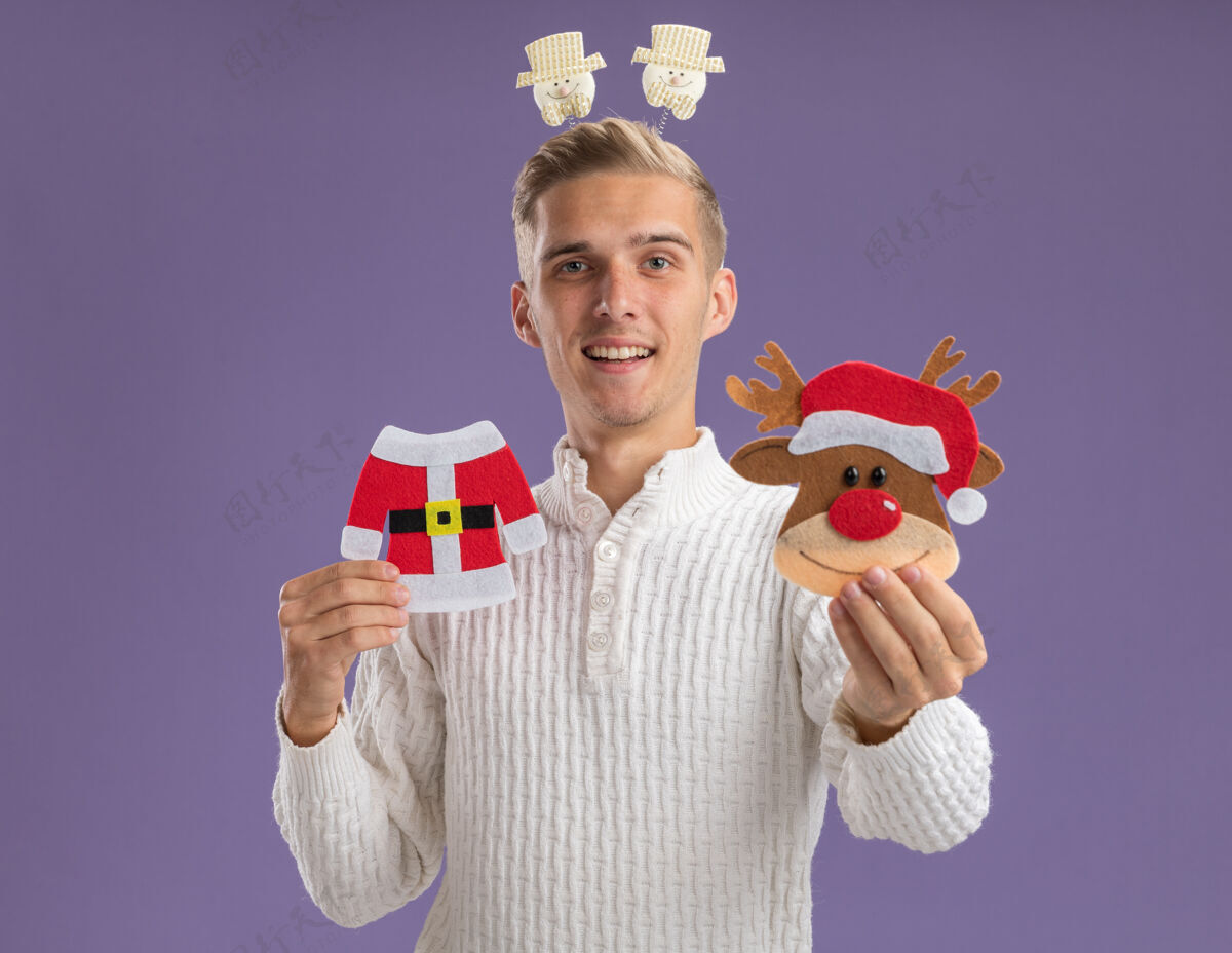 装饰品给人印象深刻的年轻帅哥戴着雪人头巾拿着圣诞纸饰品向孤零零的紫色墙上伸展穿着头带走向
