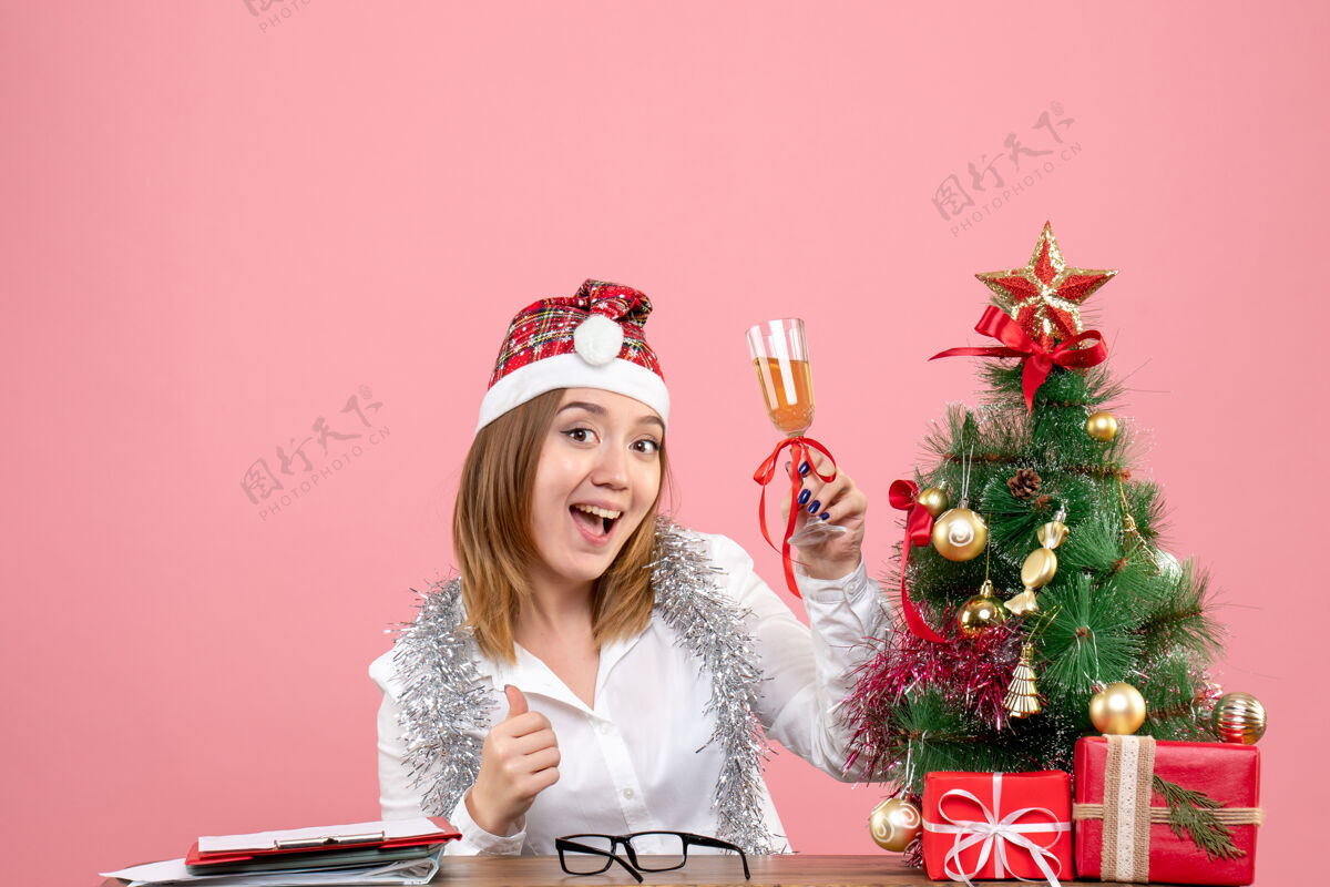 办公室女工庆祝圣诞节的正面图 粉色上有一杯香槟人们粉色香槟