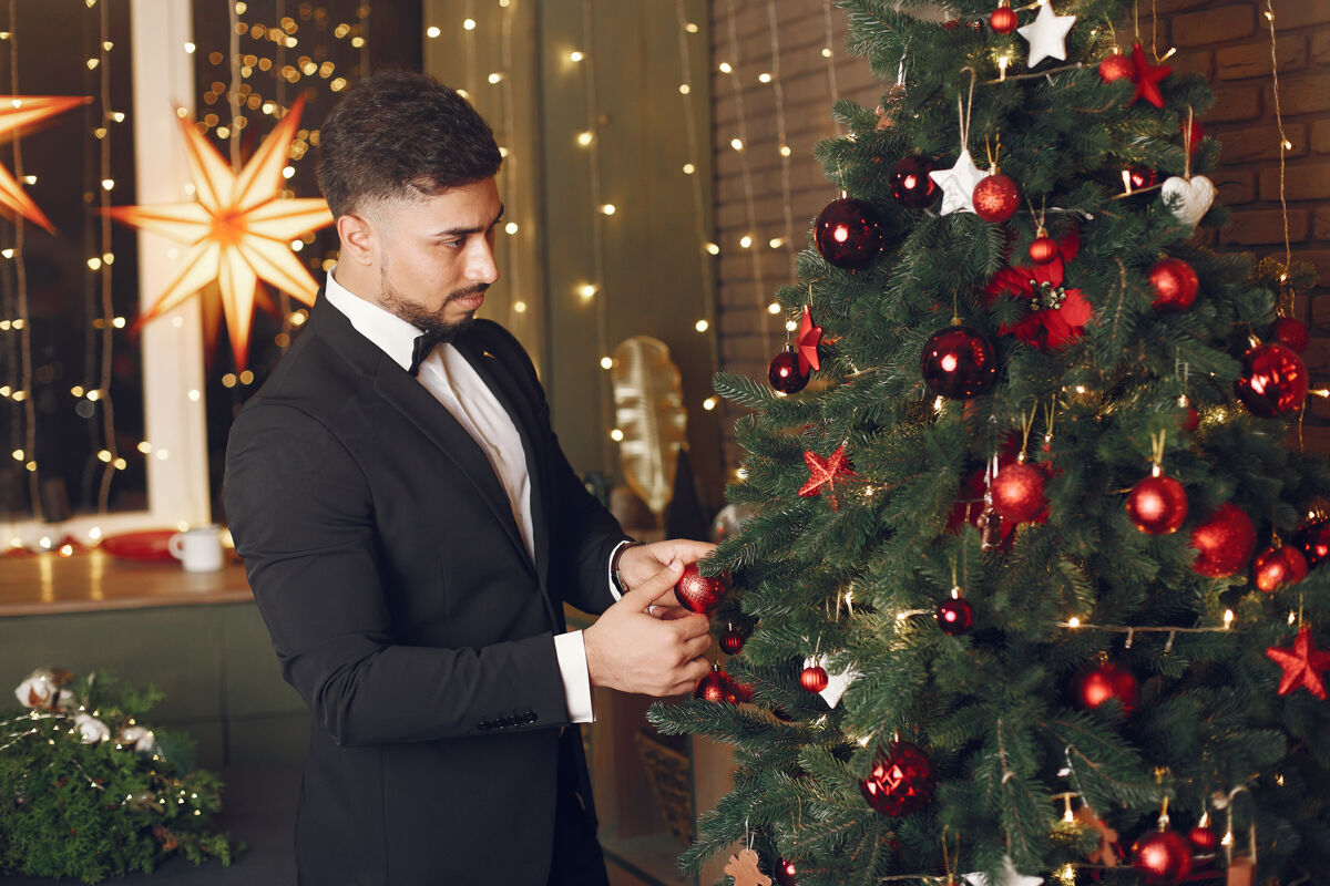 人圣诞树附近的帅哥穿着黑色西装的绅士男人灯光领带