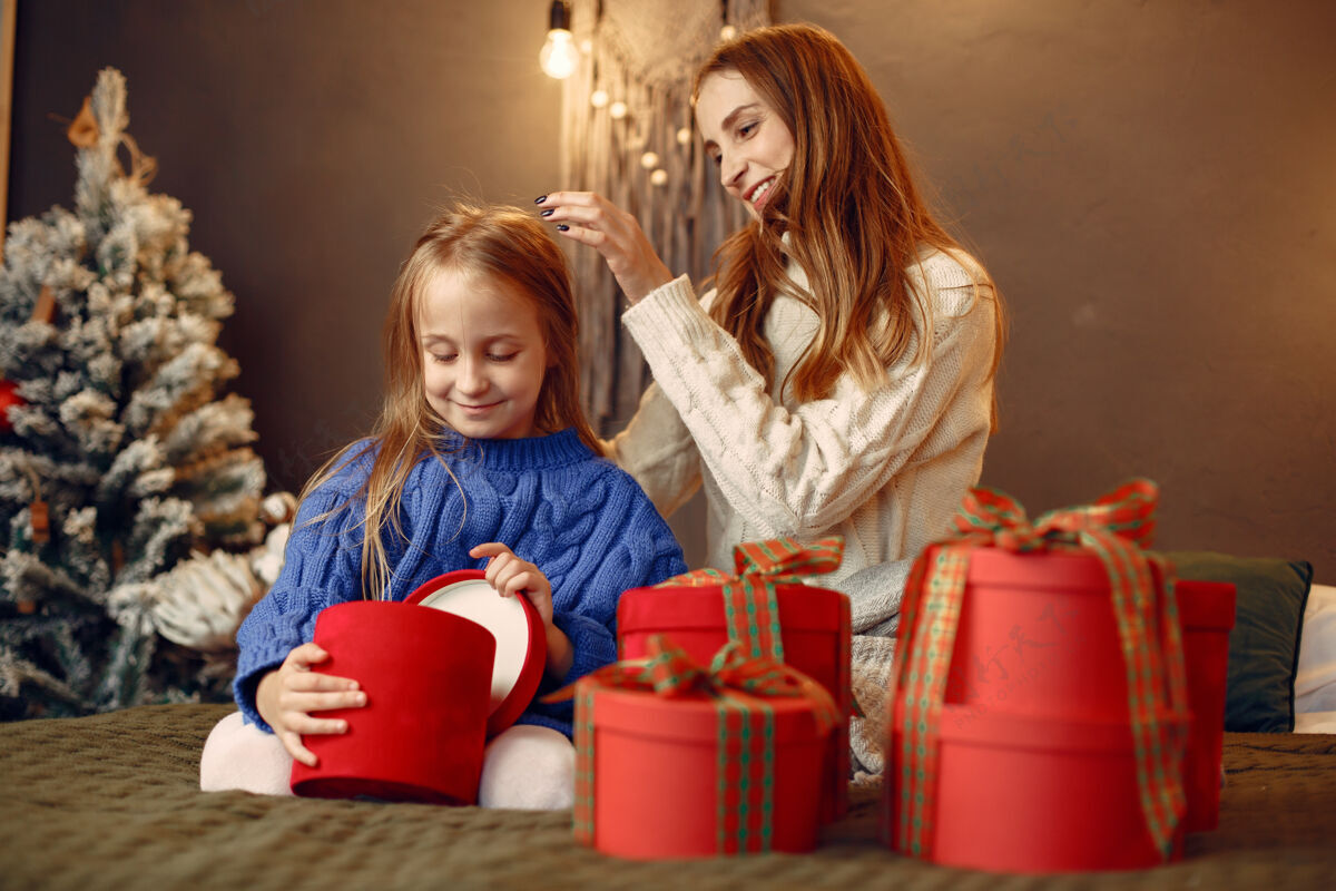 女孩人们在为圣诞节做准备母亲在和女儿玩耍一家人在节日的房间里休息孩子穿着蓝色毛衣碗装饰爱