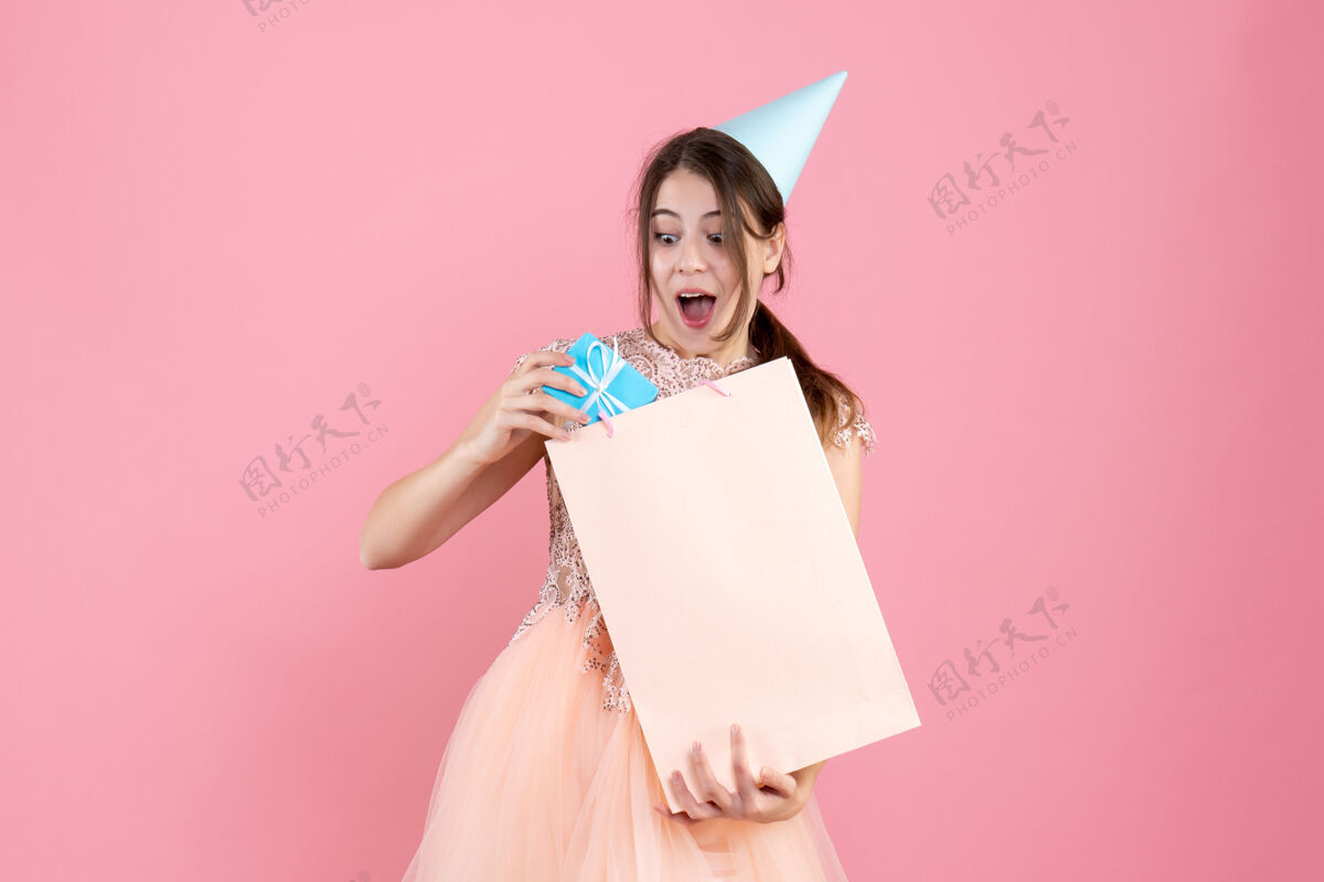 人戴着派对帽的派对女孩把礼物放在粉红色的袋子里女士礼物服装