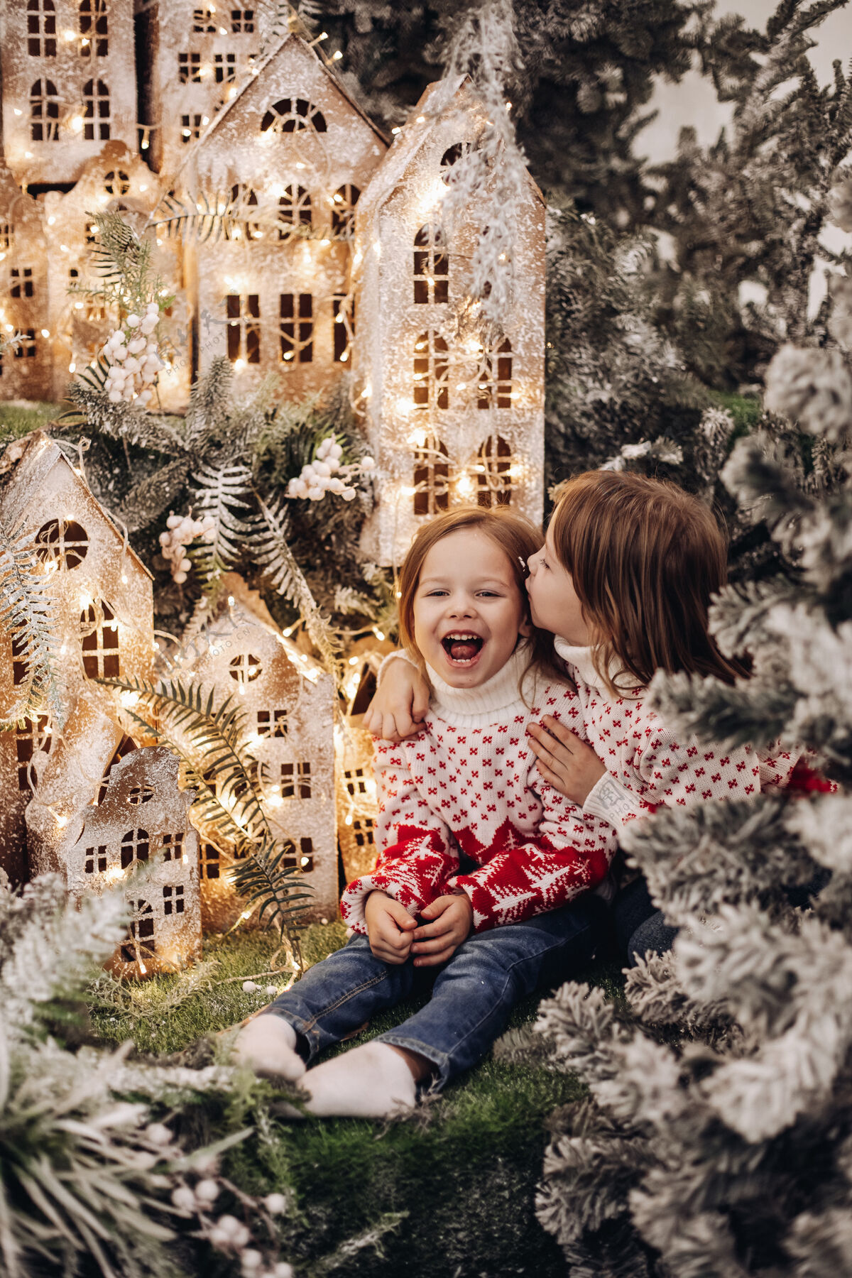 圣诞两个白人姐妹在一个美丽的圣诞装饰中对着镜头摆姿势 雪地里有很多树冻结童年装饰