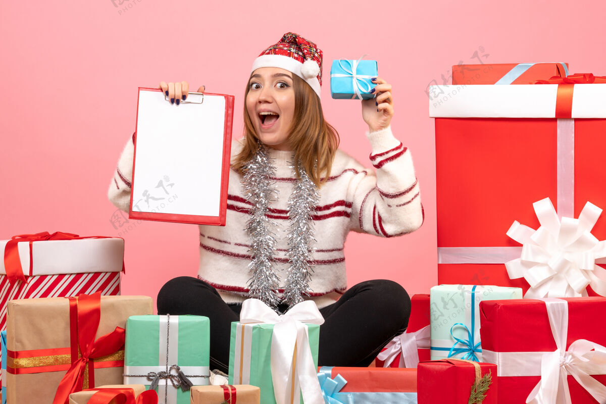 年份前视图年轻女性围坐在圣诞节礼物与文件说明礼物粉色桌子