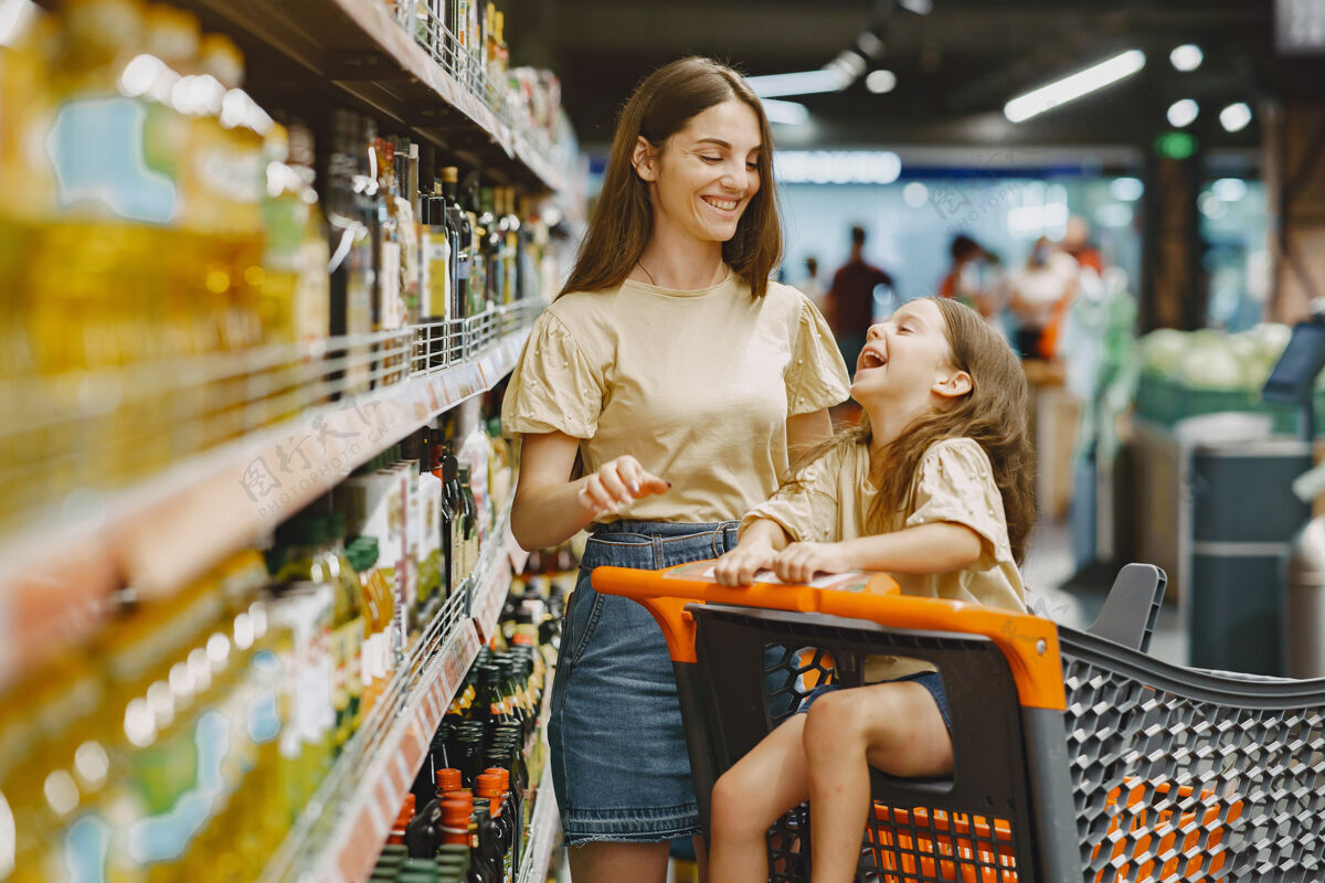 零售一家人在超市一个穿棕色t恤的女人人们选择产品母亲带着女儿消费主义产品人