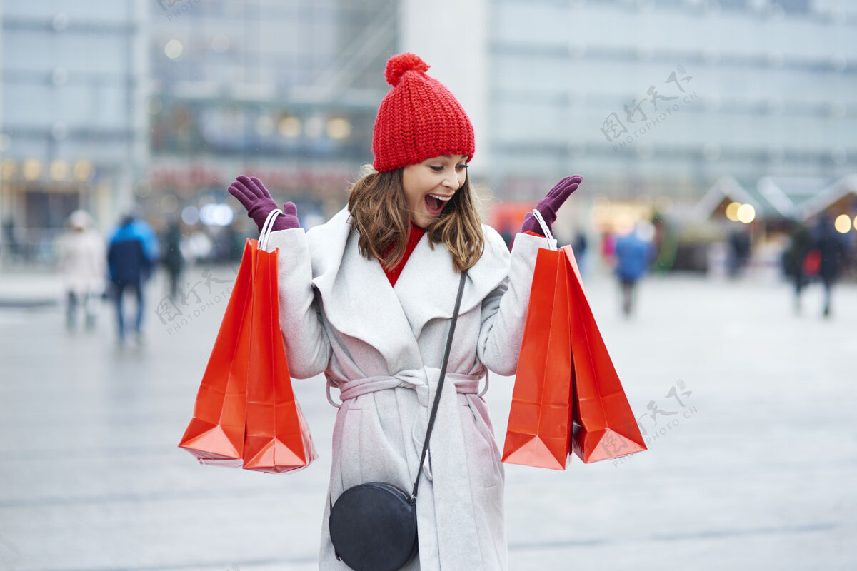 帽子美丽的女人在冬季购物时带着包冷购物袋人
