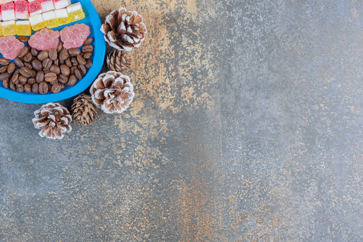食物一个蓝色的板上装满了不同的果冻糖果和松果高质量的照片调味点心美味
