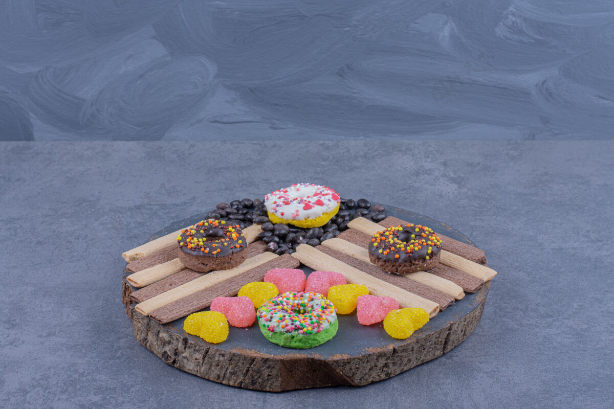 盘一个装满甜甜圈和心形果冻糖果的深色盘子成型食物吃