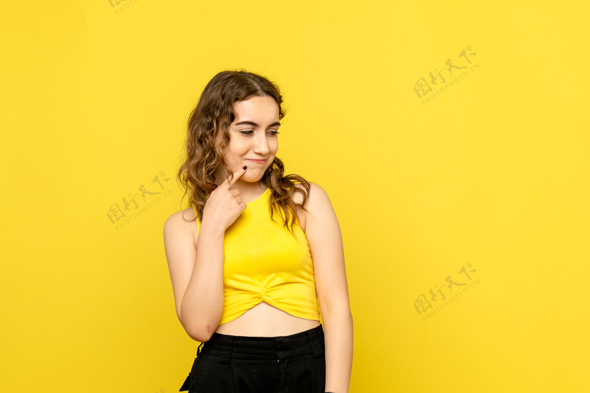 漂亮黄色墙壁上微微微笑的年轻女子的正面图女士女性年轻女性