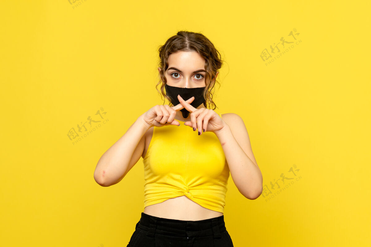 年轻女性黄墙上戴着面具的年轻女子的正视图流行前面漂亮