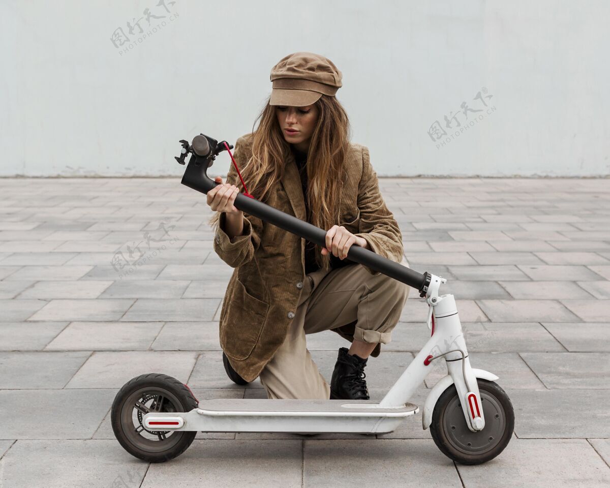 年轻拿着她的电动滑板车的年轻女人城市交通女士城市