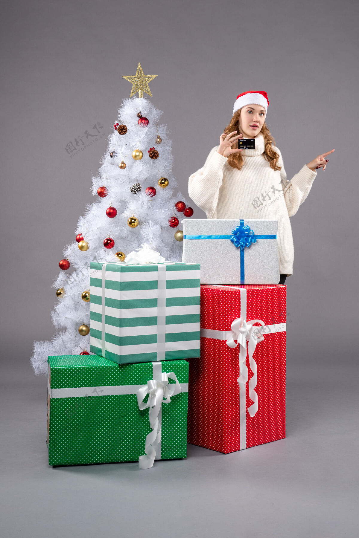 圣诞老人年轻的女性在灰色的圣诞礼物周围圣诞树女性帽子