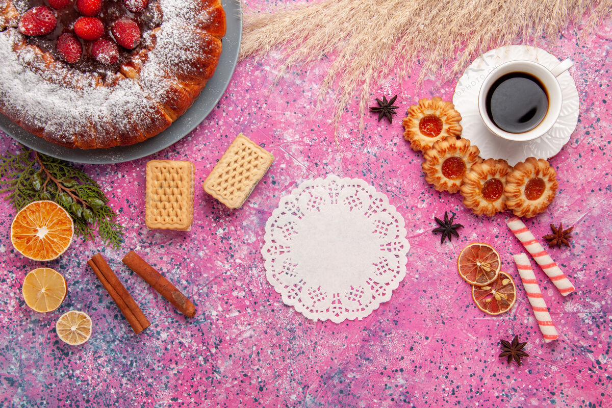 胡椒俯瞰美味草莓蛋糕配饼干和一杯茶 背景为浅粉色蛋糕烘焙甜甜饼干饼干派杯子茶灯光