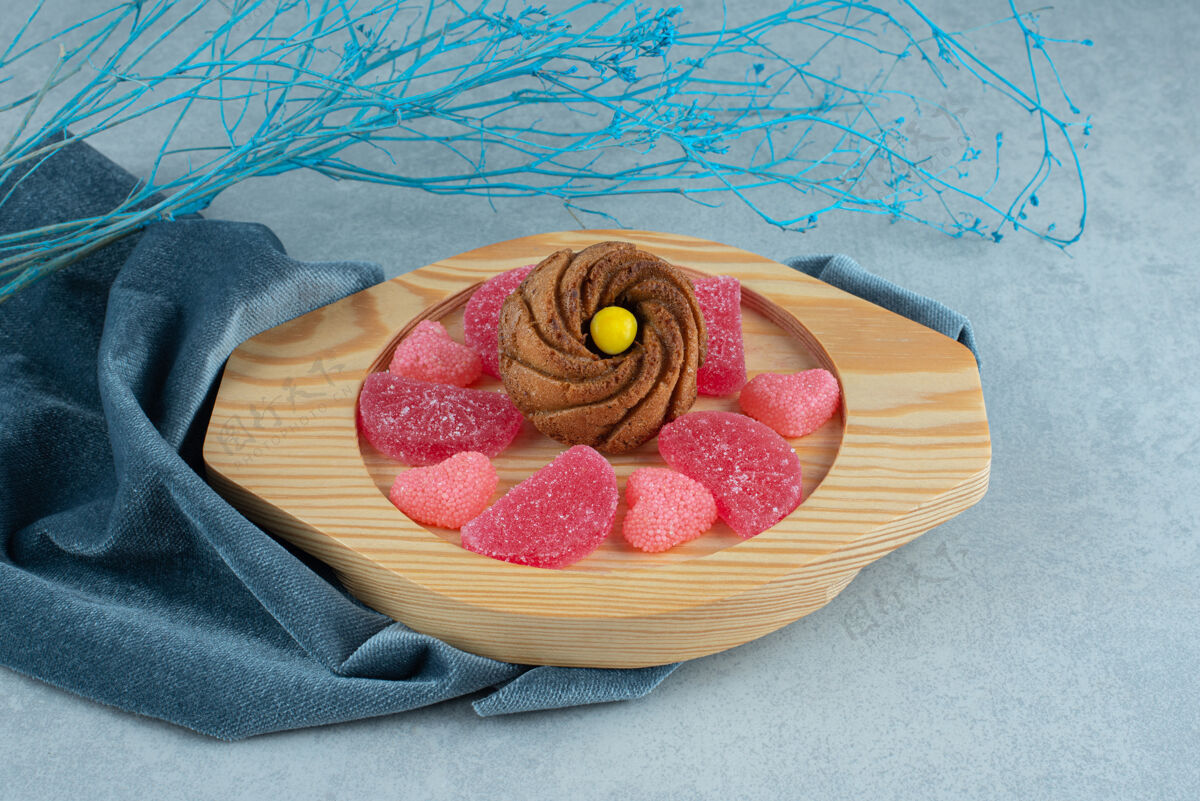 烘焙食品在大理石装饰性树枝旁边的毛巾上放上一盘饼干和marmelades甜食甜点糕点