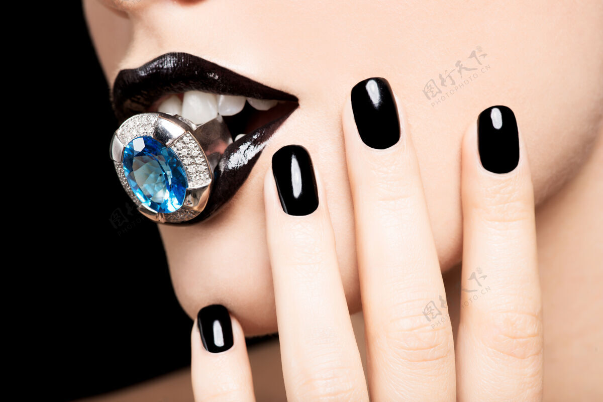 水晶一个女人的嘴唇和指甲被涂成亮黑色的宏观照片化妆品嘴唇闪亮