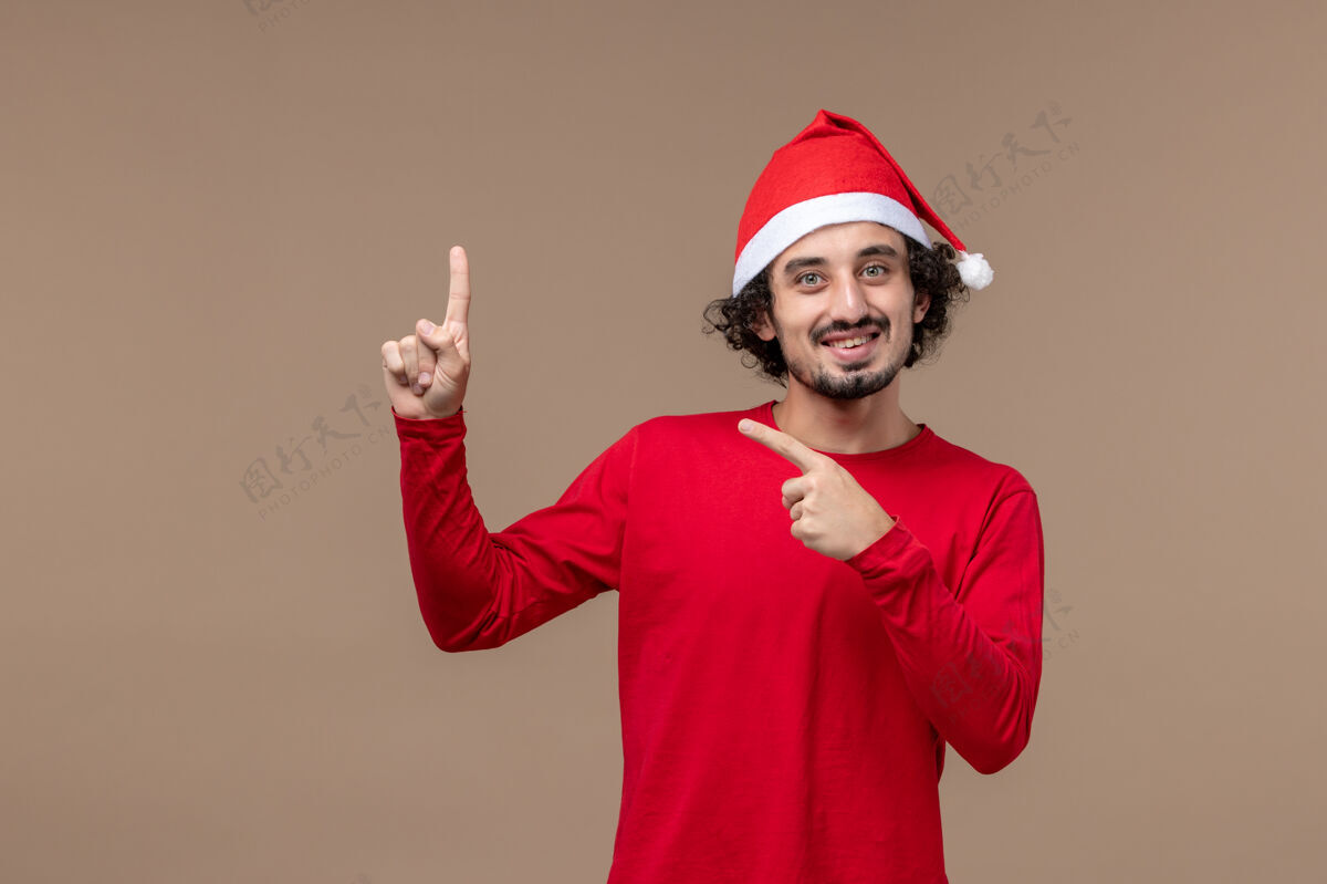肖像正面图：一个穿着圣诞斗篷的年轻人在一个棕色的背景上感慨圣诞节快乐节日工人