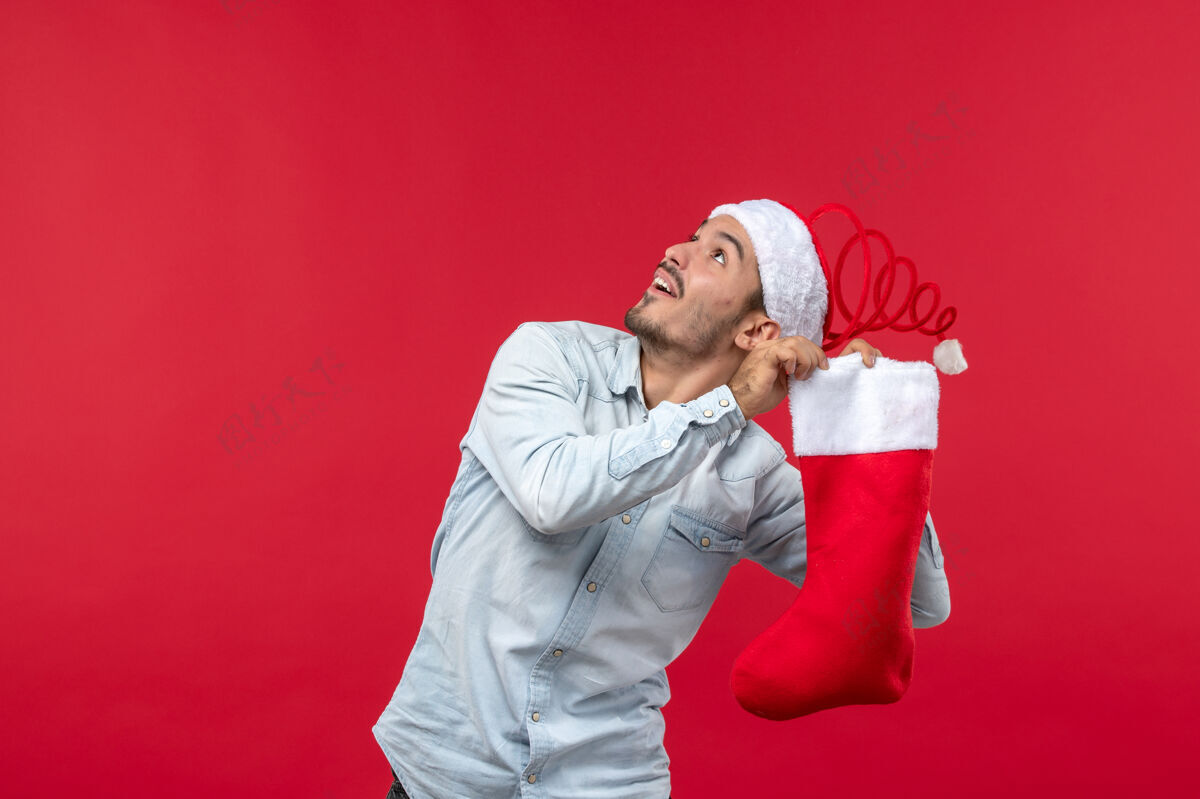 节日年轻人在红墙上与大袜子合影的正面图圣诞节休闲前面