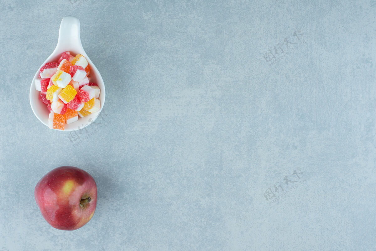 水果在大理石上放一个苹果和一小碗糖果糖营养视图