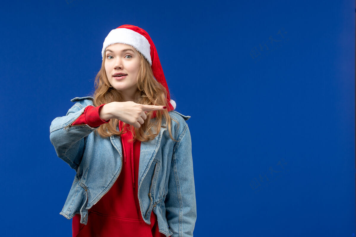 开朗前视图年轻女性 蓝色背景 红色圣诞帽 情感圣诞色红色快乐情感