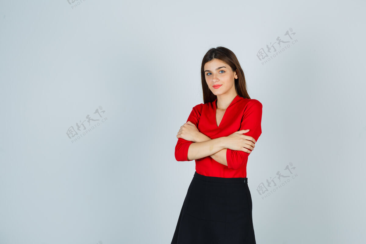 成人穿红衬衫 黑裙子的年轻女子双臂交叉站着 看上去很欢快青年人欢快