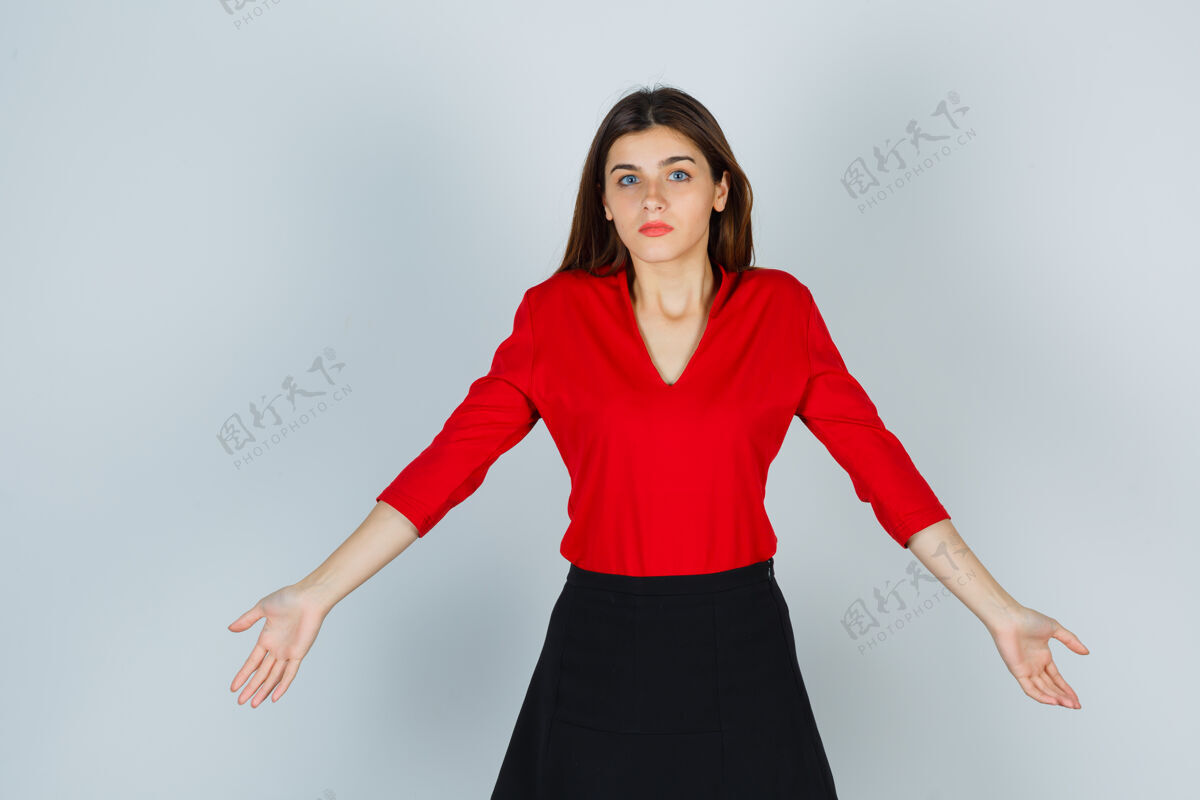 女性穿着红衬衫的年轻女士 裙子伸开双臂 看起来很无助麻烦混乱沮丧