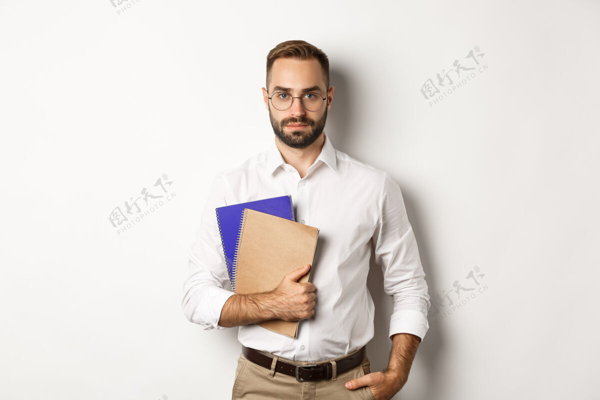 男人帅气的男员工拿着笔记本 看起来很自信 站着自信雇员衬衫